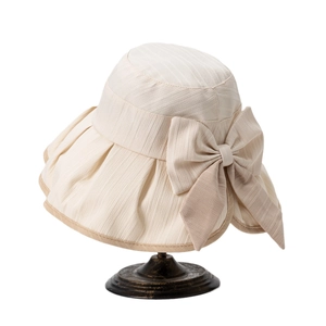 Elegant cream sun hat with large bow and wide brim on a vintage metal display stand