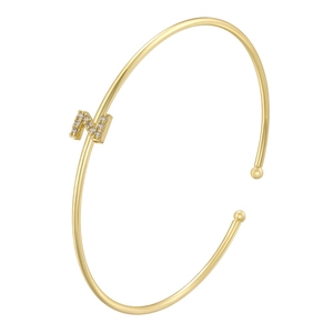 Macro detail of gold-plated open cuff bangle featuring a micro-paved zircon letter N