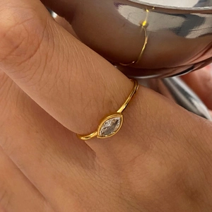 Minimalist marquise-cut clear gemstone ring with slender gold band on finger