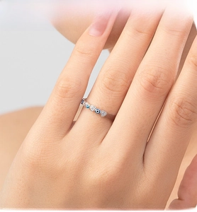 Detailed view of silver heart-shaped ring with blue evil eye charms on a hand