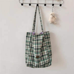Detail of green plaid canvas tote bag showing purple lining and metal hook display