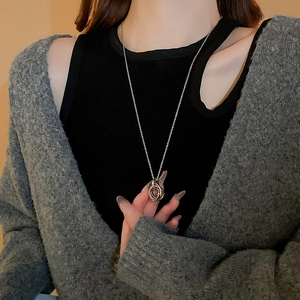 Detail of silver long chain necklace with interlocking rings worn over a cardigan