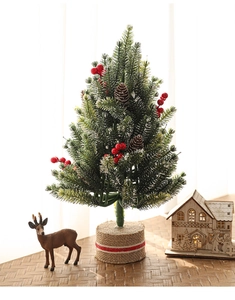 Detail of mini snowy Christmas tree with red berries, pine cones and burlap base decor