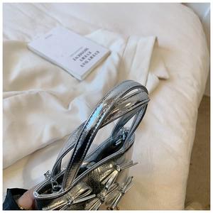 Close-up of metallic silver handbag with bow details and top handle on white surface