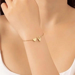 Polished gold heart and letter V pendant charms on a delicate stainless steel chain bracelet