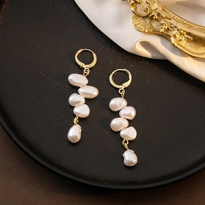Elegant gold earrings with irregular baroque pearls on black tray with white silk