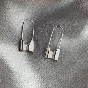 Macro shot of silver polished padlock earrings resting on dark grey silk fabric texture