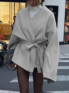 Détail d'un manteau gris oversize en laine avec tissu texturé et ceinture élégante