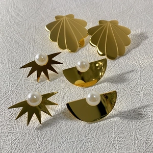 Three pairs of 18k gold-plated stainless steel earrings with white pearls on a white surface