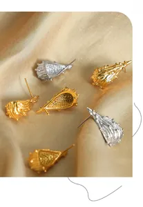 Macro-opname van bionische schelpvormige gouden en zilveren oorbellen op zijden stof