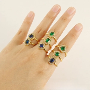 Close-up of gold titanium steel rings set with emerald and sapphire zircon stones