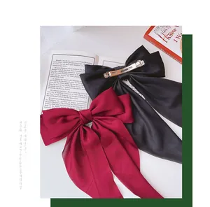 Detail of elegant oversized satin bow hair clip with long streamers and metal spring clip