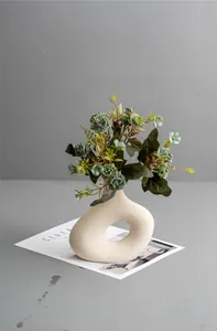 Detail of matte cream ceramic donut vase with grainy texture and blue daisy flowers