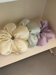 Three oversized satin scrunchies in cream, mint, and lilac colors on a shelf