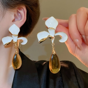 Detail of floral earring with white petals, gold edges and amber water drop pendant