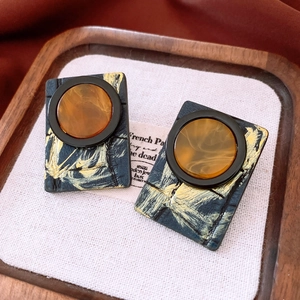Close-up of vintage geometric resin earrings with amber and blue-black color blocking