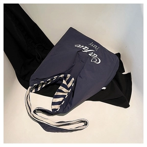Flat lay of deep blue canvas tote bag with white lettering on ivory background