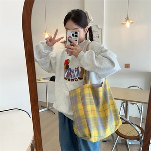 Detail of a large capacity yellow and purple plaid canvas tote bag with broad strap