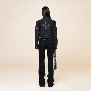 Detail view of the back of a black denim jacket featuring a cross patch design on the fabric