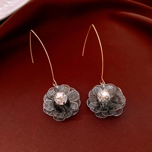 Détail de boucles d'oreilles fleur avec crochets dorés et zircons sur velours rouge