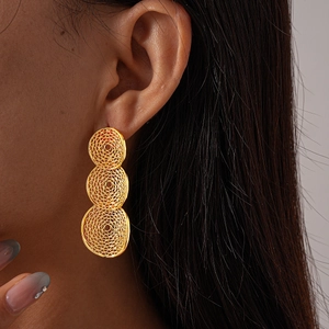 Close-up of golden geometric hollow mesh drop earrings worn by a model in a side view