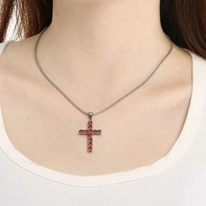 Detail of cross pendant necklace with red and orange zircon stones on a female model
