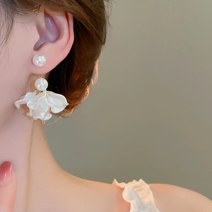 Close-up of floral tassel earrings with pearls and white resin petals on female model