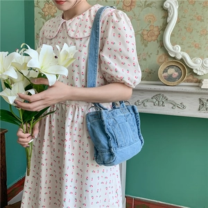 Close-up of blue denim tote bag with dual straps held by a model in a floral dress