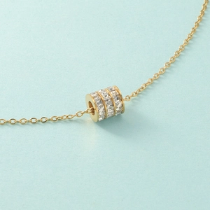 Macro shot of gold cylinder pendant with triple rows of pavé set white cubic zirconia