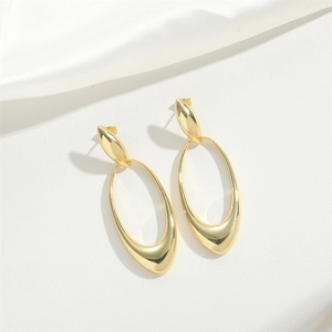 Exaggerated hollow oval gold earrings on white silk background in minimalist style