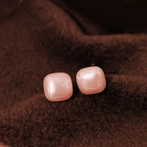 Square pearl stud earrings with soft pink luster and silver needles on a velvet texture