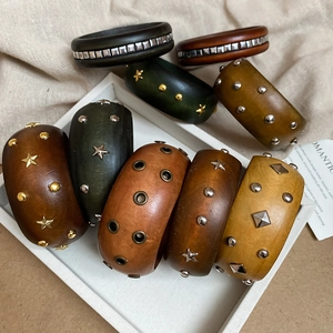 Gros plan de larges bracelets en bois vintage avec rivets métalliques tons terre