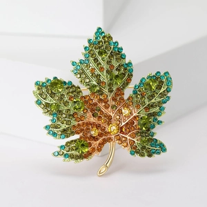 Detailed close-up of a maple leaf brooch with vibrant gradient rhinestones in gold setting