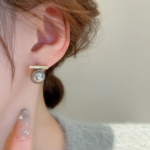 Eleganti orecchini a barra dorata con perle grigie indossati da modella di classe