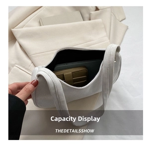 Macro view showing spacious interior of white corduroy underarm bag with phone and wallet