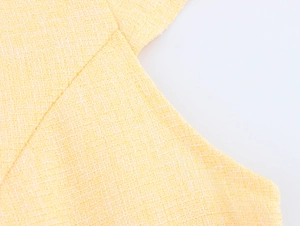 Dettaglio ravvicinato del tessuto tweed giallo con trama intrecciata del vestito