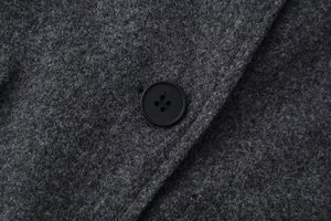 Detail of black four-hole button on dark grey woolen fabric texture and fiber