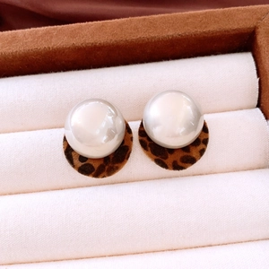 Macro view of French-style leopard print velvet earrings with pearl studs and round pendants