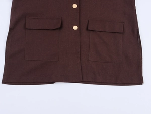 Detail of dark brown blazer featuring front flap pockets and metallic embossed buttons