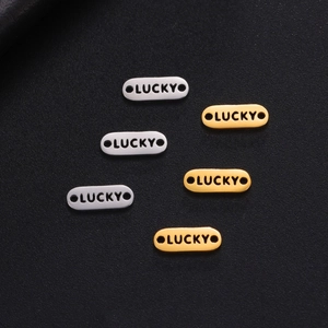 Detailed view of oval gold and silver stainless steel charms engraved with LUCKY text