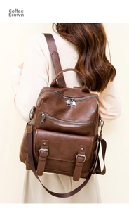 Detail of coffee brown leather backpack showing metal zippers and fringe tassels