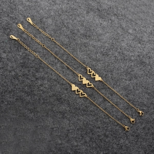 Three interlocking gold heart bracelets with solid and hollow designs on gray background