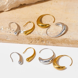 Minimalist gold and silver C-shaped hoop earrings on elegant beige stone base