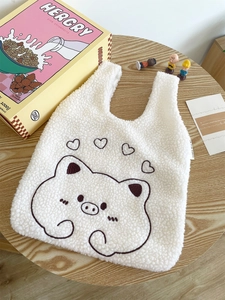 Detail of white plush lamb wool tote bag featuring a brown embroidered cartoon pig pattern