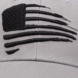 Detailed close-up of textured black American flag embroidery on grey mesh baseball cap