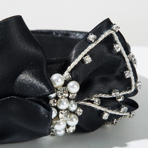 Détail d'un serre-tête en satin noir avec des perles de luxe et des strass brillants