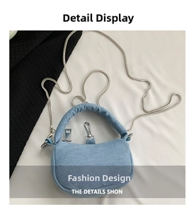 Detail view of mini blue denim handbag with silver chain strap and top handle