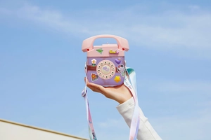 Creative telephone shaped water bottle with colorful adjustable strap against a clear blue sky