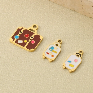 Macro shot of stainless steel suitcase pendants with colorful enamel on beige fabric