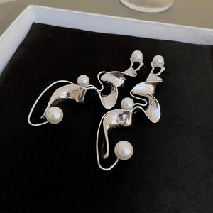 Macro detail of silver twisted metal earrings with elegant faux pearl accents